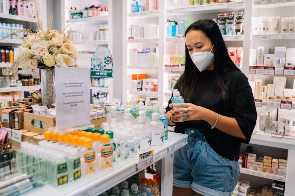 pexels-photo-5910953 Asian woman selecting hand sanitizer in a well-stocked pharmacy, emphasizing health and hygiene.